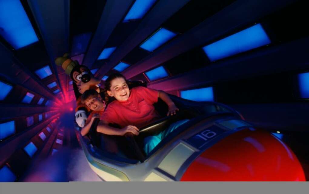 kids taking a ride on the rollercoaster Space Mountain with Goofy at Magic KIngdom