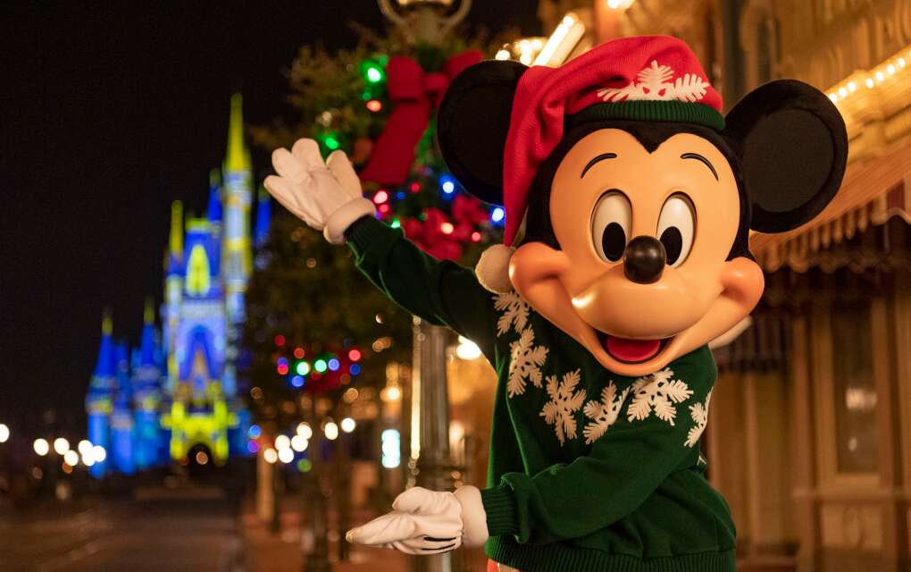 Mickey in a Christmas ugly sweater in front of Disney Magic Kingdom castle