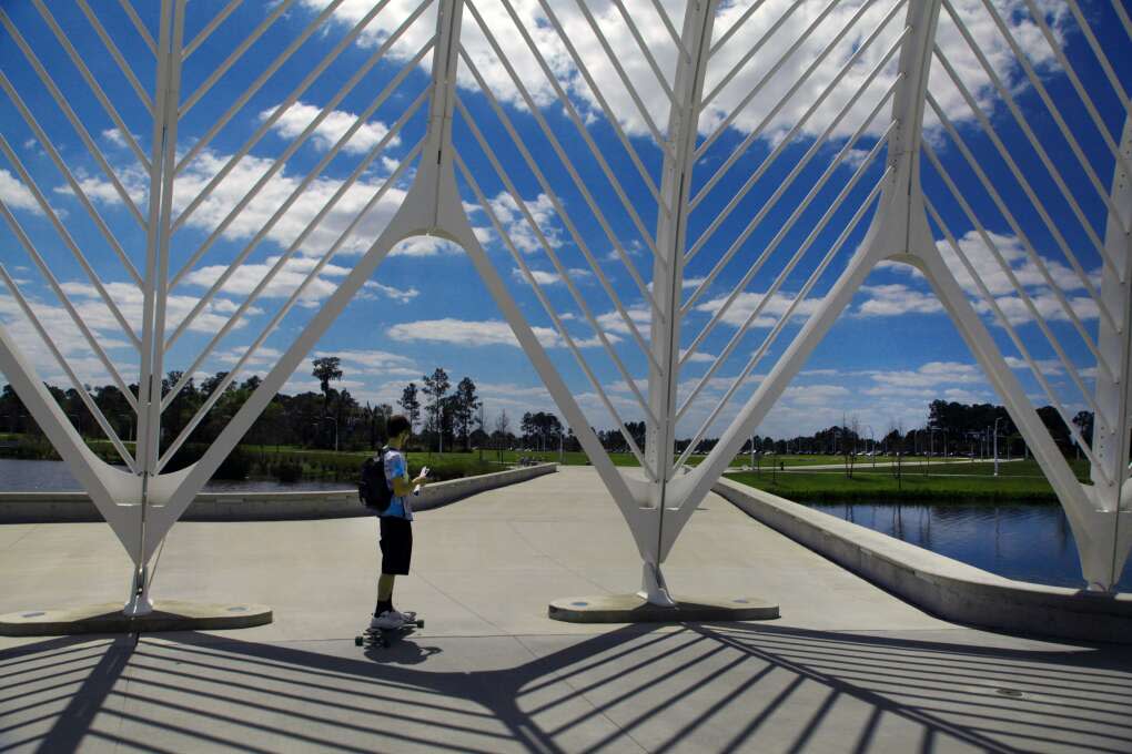 Just outside the main entrance of Florida Polytechnic University, a student skateboards away from the building.
