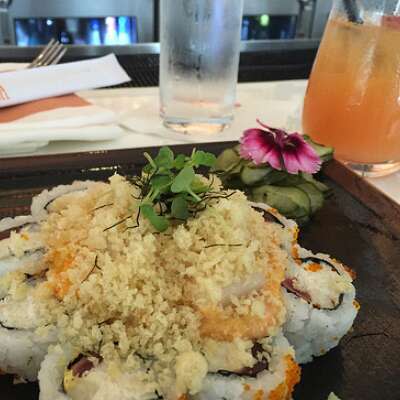 a plate of delicious sushi next to a fruity cocktail at a restaurant