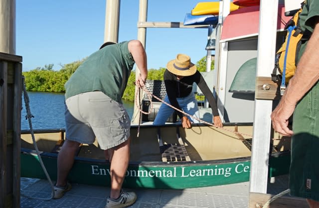 Two men putting a green boat from the Environmental Learning Center in the water