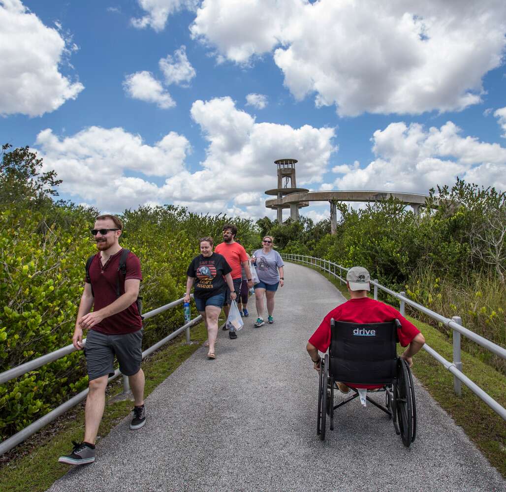 young man in a wheelchair makes his way toward the Shark Valley Tower in Everglades National Park. Park trams are equipped to transport visitors with disabilities to the tower.