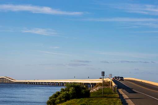 Motorists drive the sunlit causeway from the mainland to St. George Island on the Coastal Trail of the Big Bend Scenic Byway.