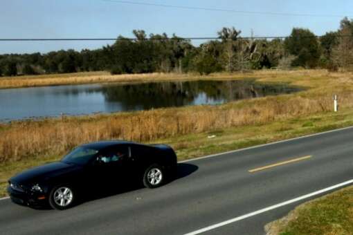 A car passes a lake along the Scenic Sumter Heritage Byway near Sumterville, Fla.