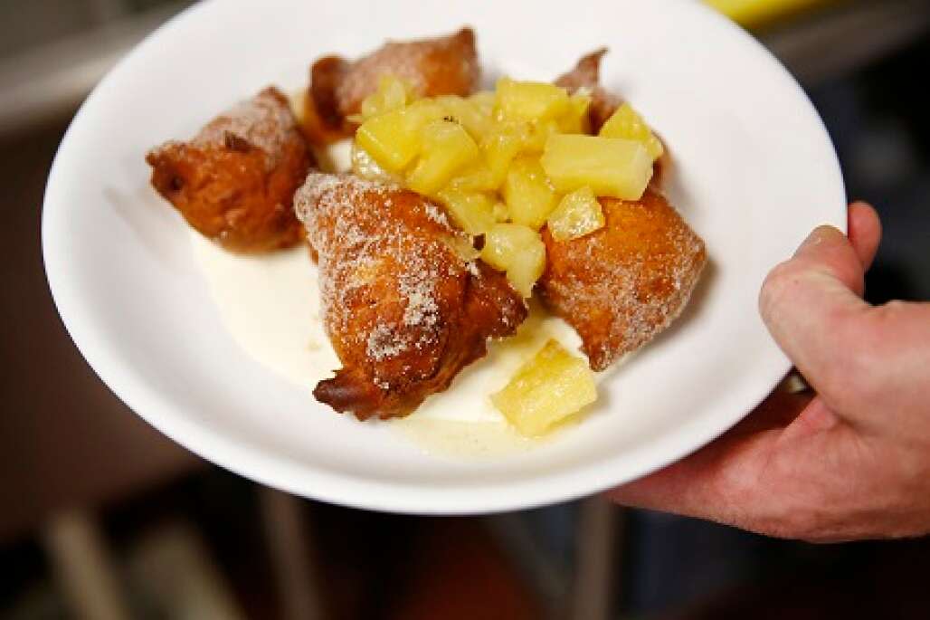 Owner/Chef Jeff Mitchell carries a doughnut-like pineapple-topped desert, Ricotta Zeppole, at The Local Restaurant.