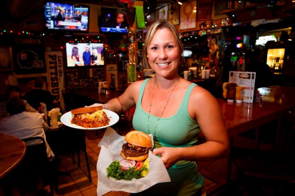 A waitress serves up a Texas Chili Burger (left) and a Full Service Burger at Johnny’s Fillin’ Station in Orlando.