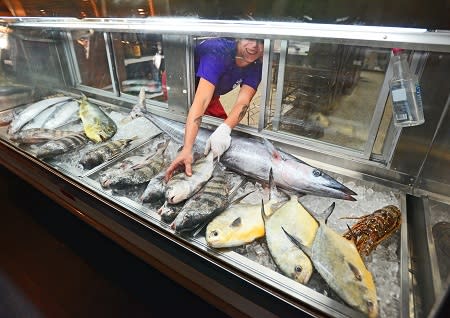 A person grabbing a fish from the fish display