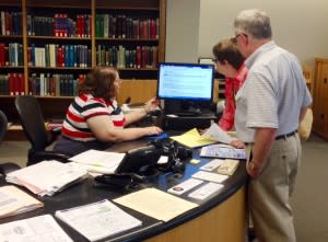 Librarian Delia Bourne helps people at the Genealogy Center desk. 