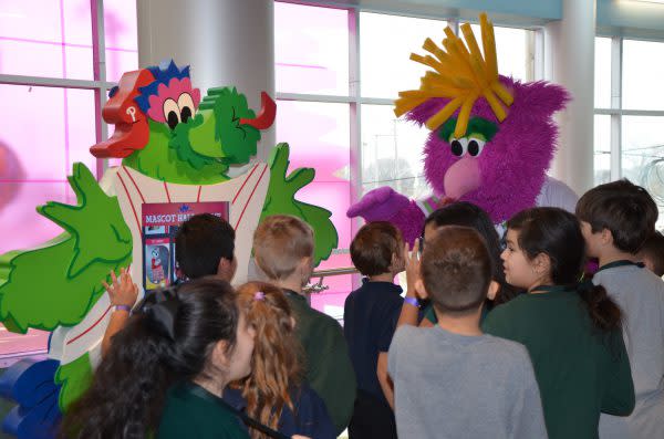 Reggie the mascot gives kids high fives at media day.