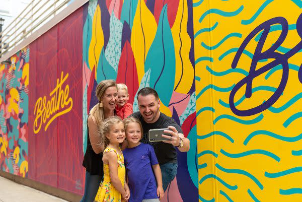 Family posing for a selfie in front of the Breathe Mural in downtown Fort Wayne, Indiana