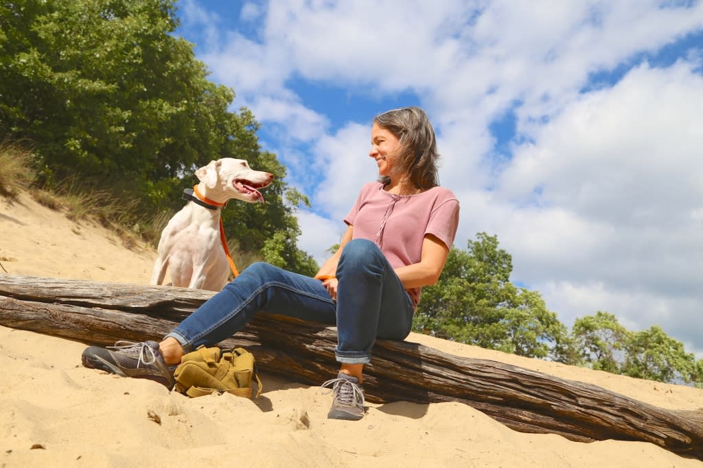 A woman and her dog sitting on the beach