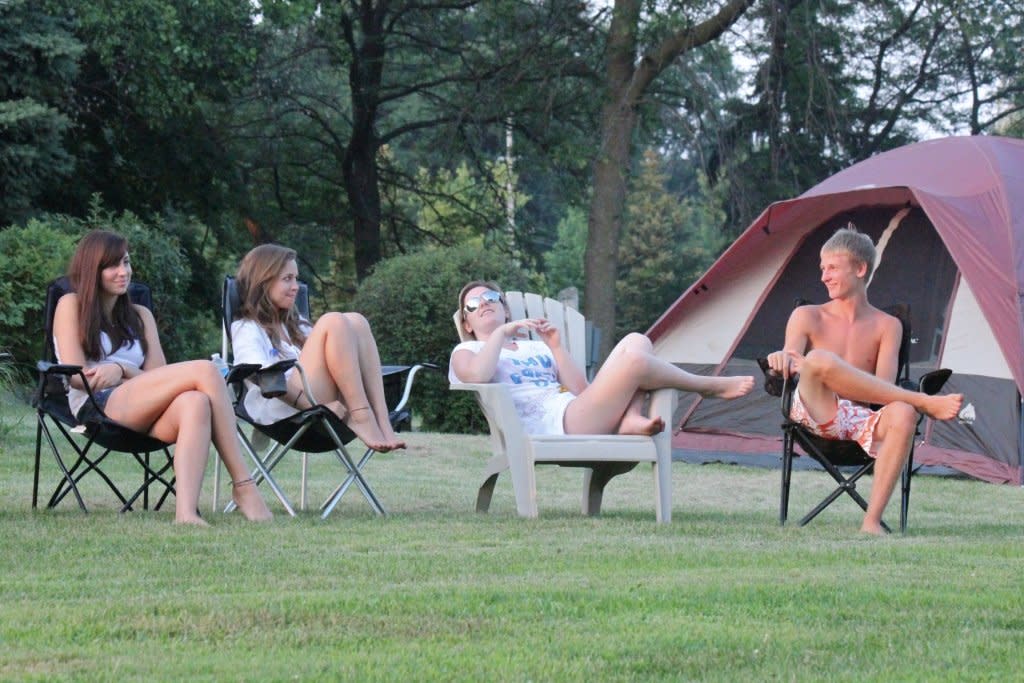 Several young people are sitting in lawn chairs in front of a tent