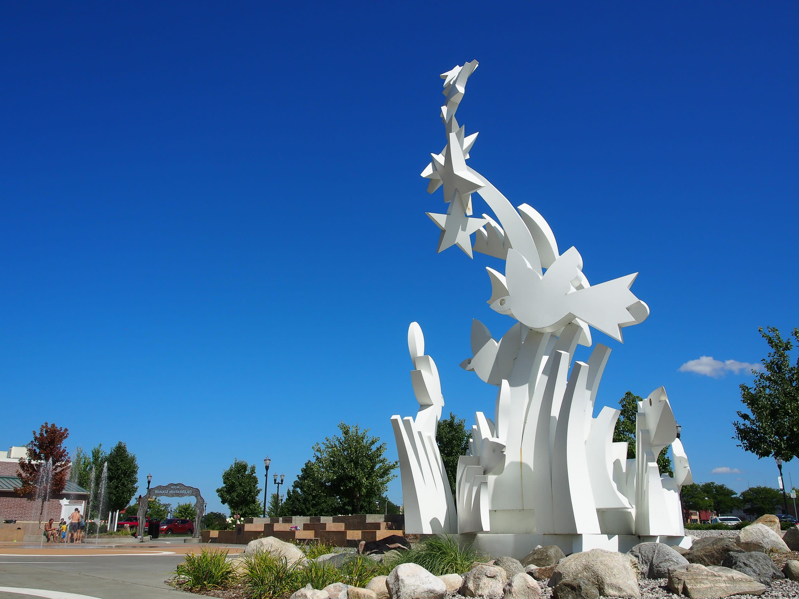 white sclulpture with stars and bird shapes is set against bright blue sky