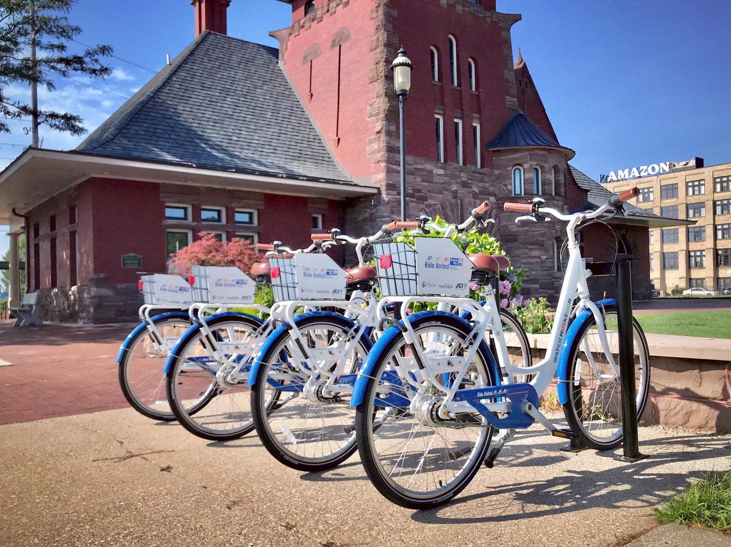 4 blue rental bikes lined up at bike rack in front of historic red brick building