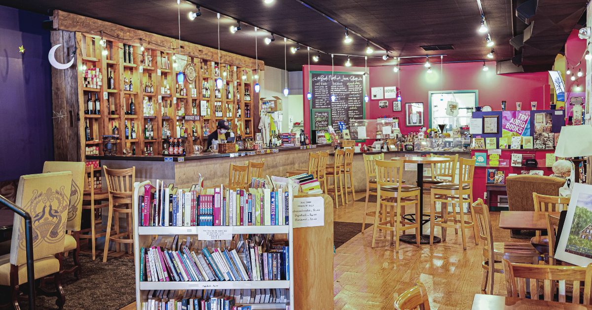 interior of book store and cafe. cart of book in foreground. cafe counter runs along side and back of photo