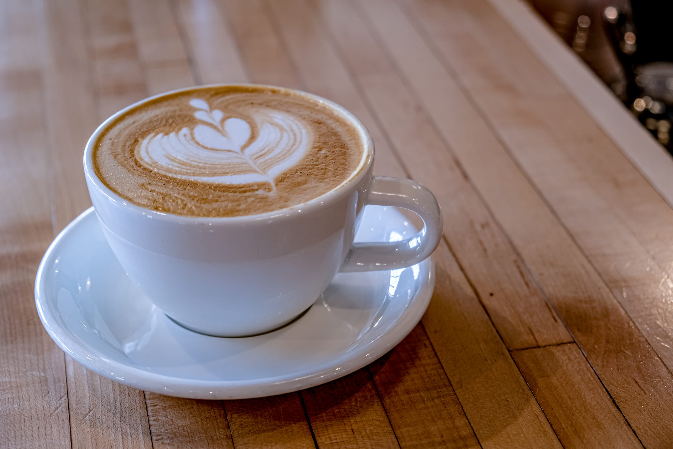 coffee with heart design sits on wooden top table