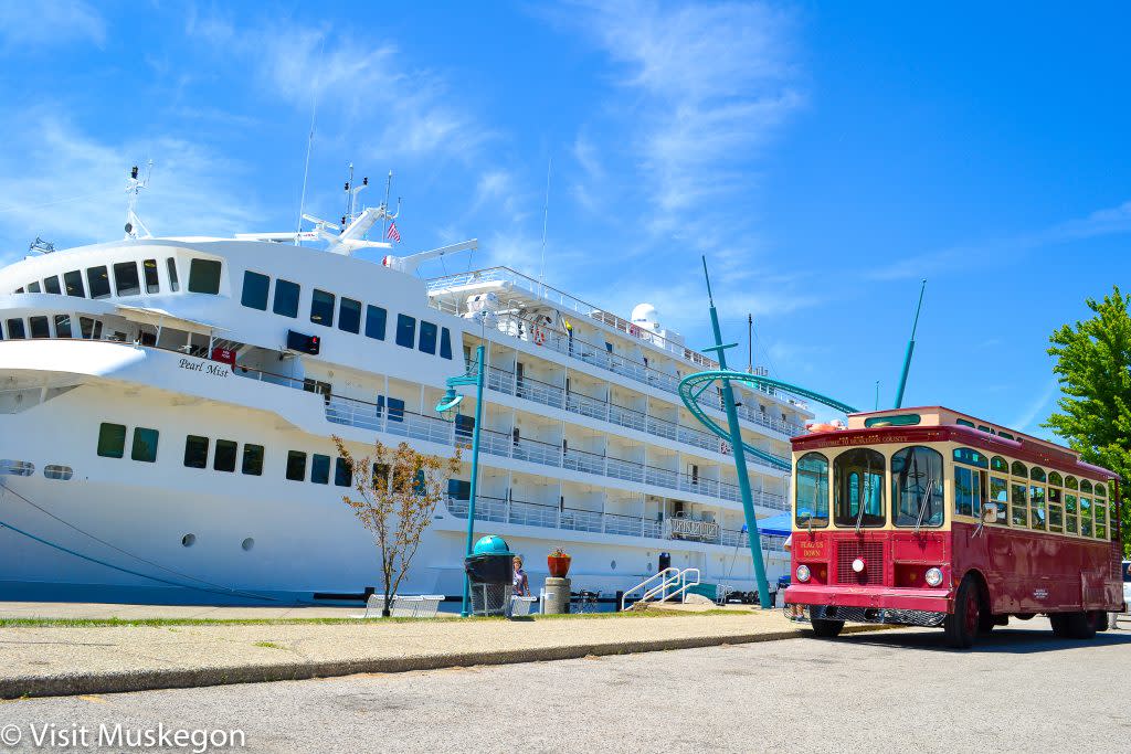 red trolley sits in front of white cruise ship under bright blue sky
