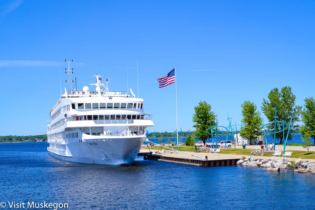 pearl mist cruise ship docked at heritge landing in muskegon michigan. american flag waves over white ship against blue skies and water