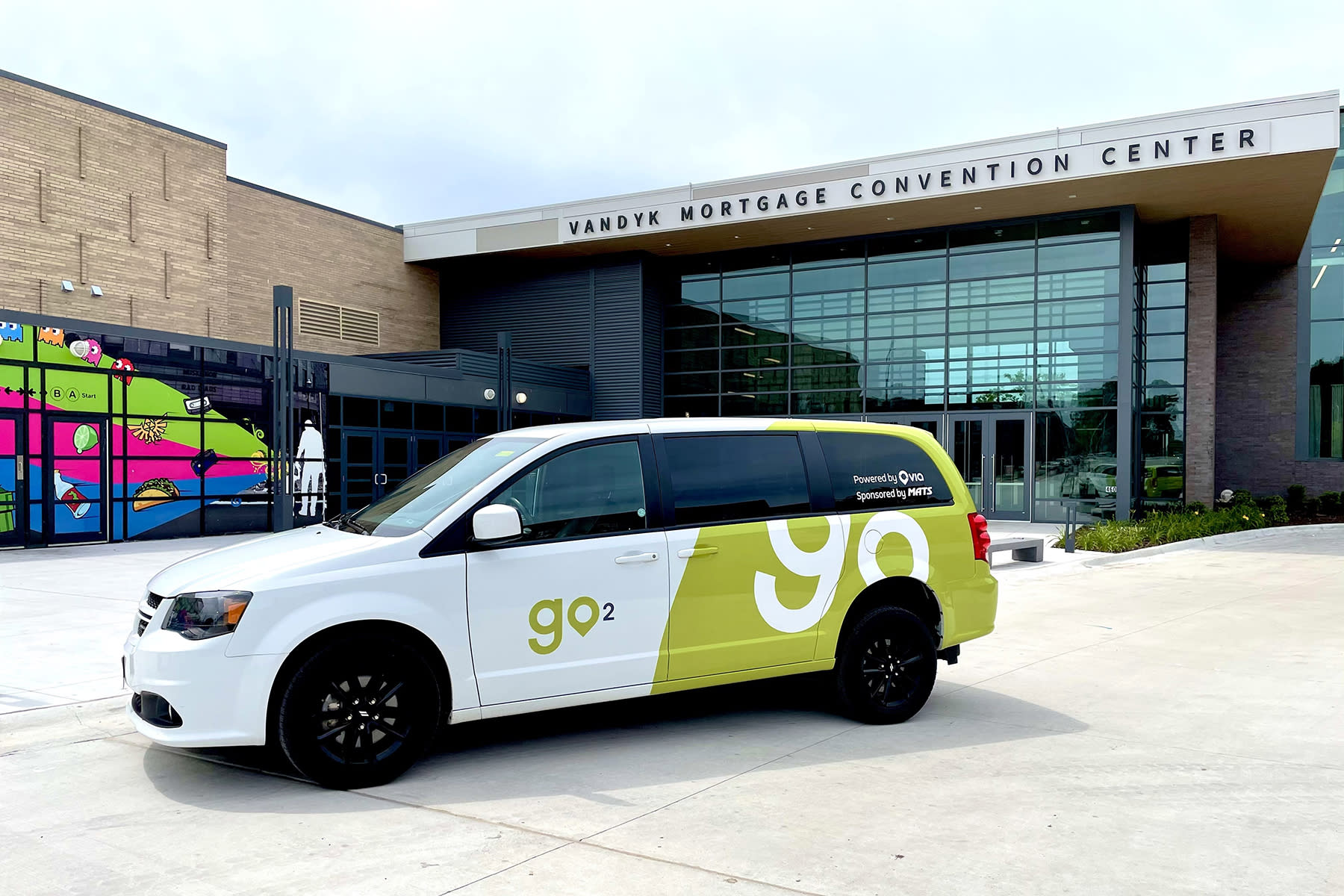 Green and white microtransit Go2 in front of Convention Center