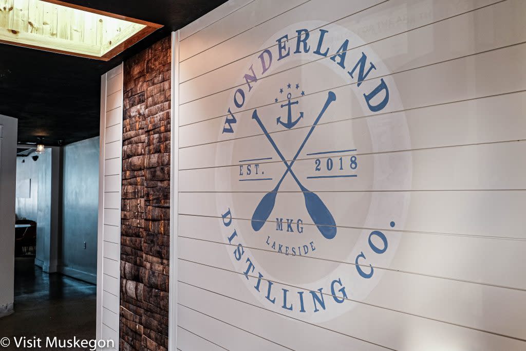blue logo on slatted white wall says wonderland distilling co wiht image of crossed boat oars in center