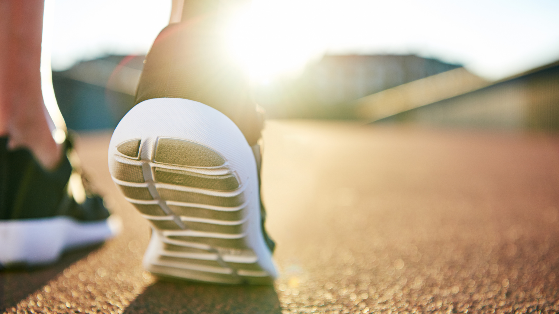 heel of running shoe on track with sunflare in background