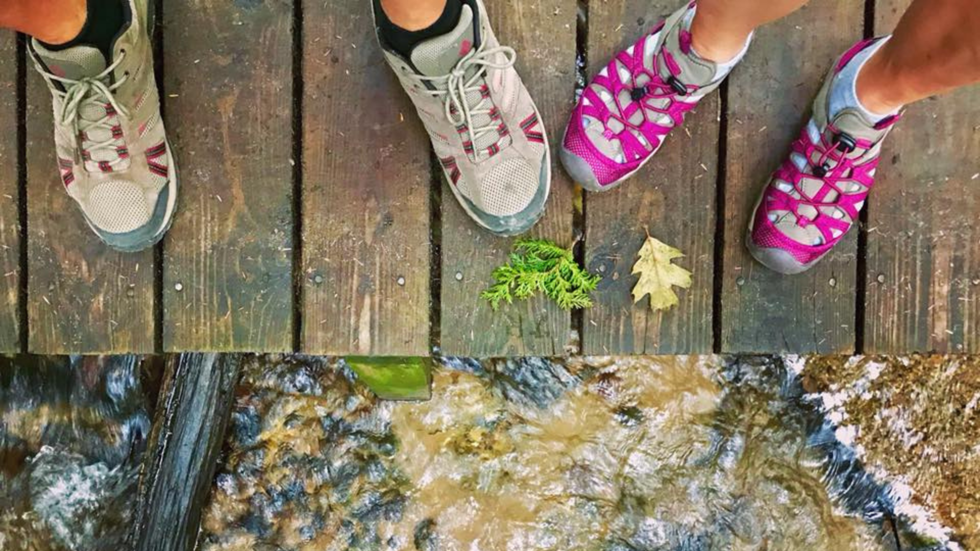 overhead shot of mens and woman's hiking shoes on wooden footbridge