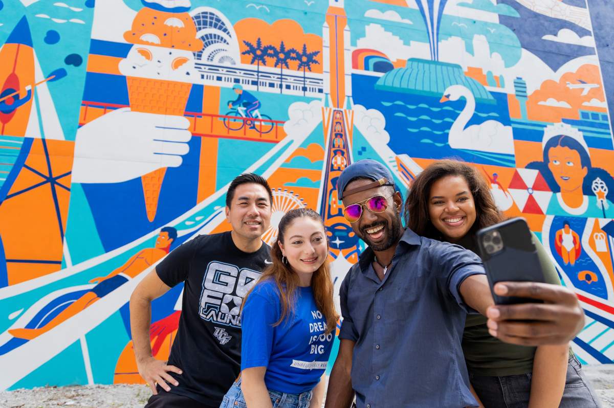 Orlando residents in front of a colorful city mural used in Visit Orlando's 407 Day coverage