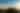 La imagen captura la silueta de tres personas en la cima de una escarpada montaña, probablemente el Volcán Barú, al amanecer o al atardecer, con el sol brillando intensamente a un lado. Debajo de ellos, un mar de nubes se extiende hasta el horizonte, creando un paisaje impresionante y una atmósfera de majestuosa tranquilidad.