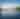 A kayaker is in the middle of a large mountain lake in autumn.