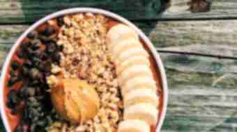 Two smoothie bowls filled with sliced bananas, oats, chocolate chips and peanut butter