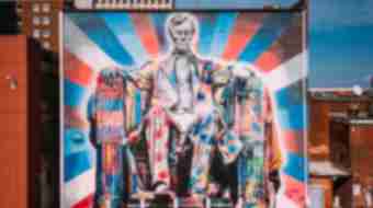 A large mural of Abe Lincoln sitting painted in brightly colored patterns primarily with red, blue, and white.