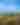 two people stand on a cliffside overlooking a great wooded landscape below