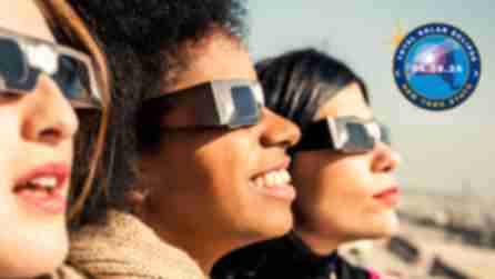 Three women with protective eyewear marvel at the moon covering the sun during a solar eclipse