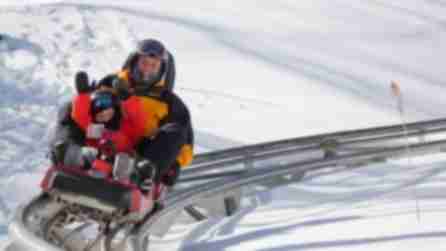 Holiday Valley Mountain Coaster A man and child ride a coaster on rails through the snow