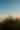La imagen captura la silueta de tres personas en la cima de una escarpada montaña, probablemente el Volcán Barú, al amanecer o al atardecer, con el sol brillando intensamente a un lado. Debajo de ellos, un mar de nubes se extiende hasta el horizonte, creando un paisaje impresionante y una atmósfera de majestuosa tranquilidad.
