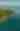 Aerial view of a lush green forest atop rocky cliffs bordering the clear blue waters of Lake Superior. The peaceful scene conveys a sense of tranquility and natural beauty.