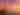 A red and white lighthouse stands on a pier beside calm water as the sky glows orange, pink, and purple at sunset.