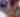 Person smiling while listening to someone else talk in a crowd