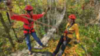 Two people on zipline at Boone Creek Outdoors in the fall.