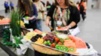 A woman gets fruit off of fruit platter.
