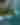 : Aerial view of a small tropical island with lush vegetation, a white sand beach, and surrounding turquoise waters with coral reefs and gentle waves