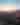People watching sunset on a patio overlooking the beach with a firepit