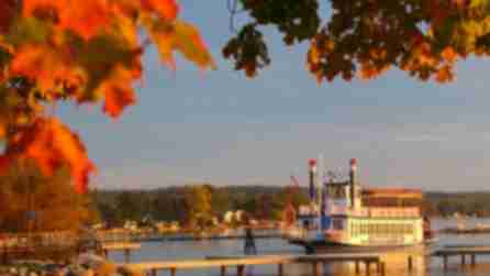 The Canandaigua Lady, a replica of a 19th-century double-decker paddlewheel boat, on the lake at sunset surrounded by fall foliage