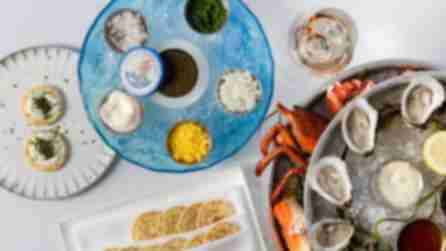 Plates of oysters, lobster,  and other food on a white table