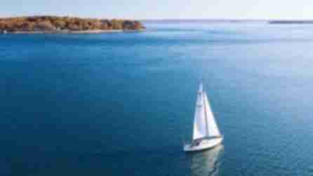 A white sailboat sailing through Greenport in Long Island