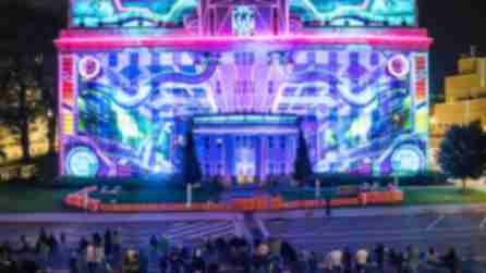 A colorful projection lights up a building at the LUMA Projection Arts Festival
