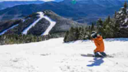 A person in an orange jacket skis down a snowy Whiteface Mountain