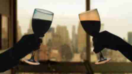 Two wine glasses about to clink with background view of Manhattan