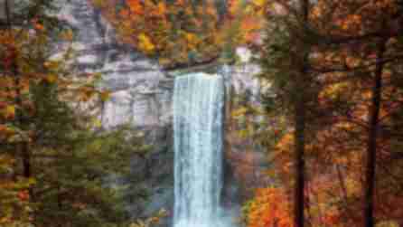 A waterfall sits among trees with orange leaves