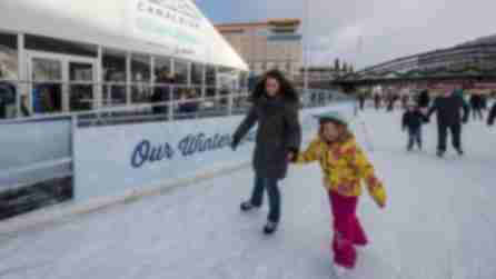 A woman and young girl hold hands while they ice skate at Buffalo's Ice at Canalside